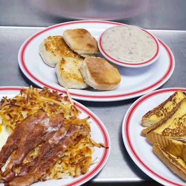 Plates of biscuits and gravy, hash browns with bacon, and French toast from Unique Coney Island.