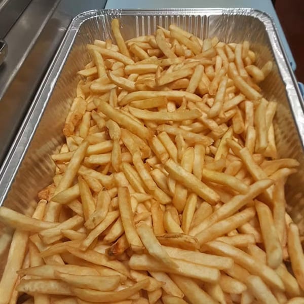 A large aluminum tray filled with golden-brown french fries from Unique Coney Island.