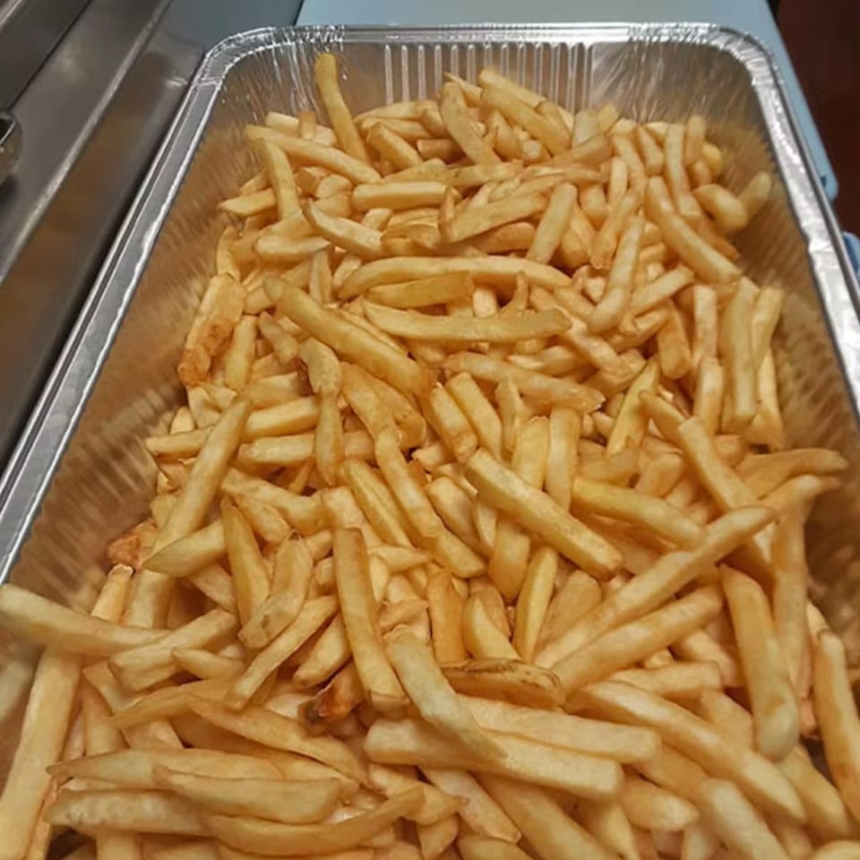 A large aluminum tray filled with golden-brown french fries from Unique Coney Island.